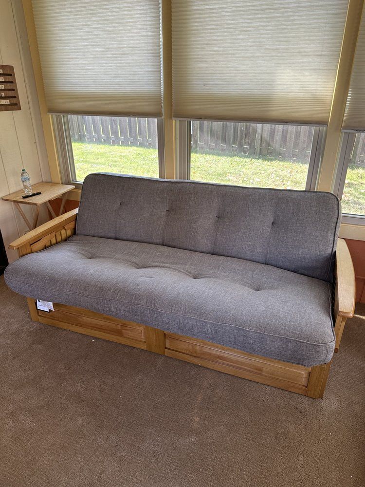 A futon is sitting in a living room next to a window.