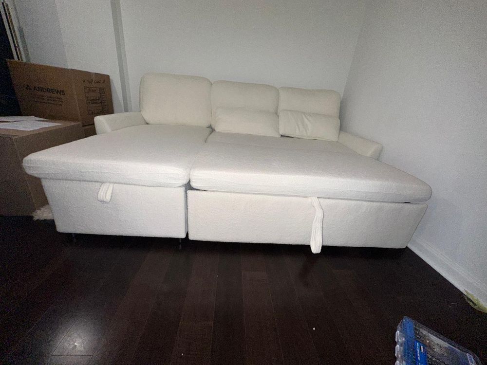 A white sectional couch is sitting on a wooden floor in a living room.