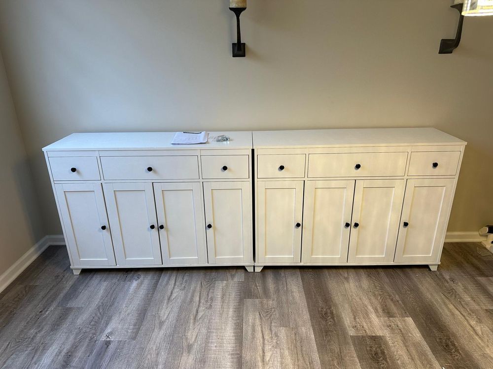 Two white cabinets are sitting next to each other on a wooden floor.