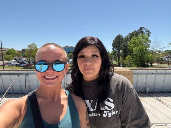Two women are posing for a picture and one of them is wearing sunglasses.