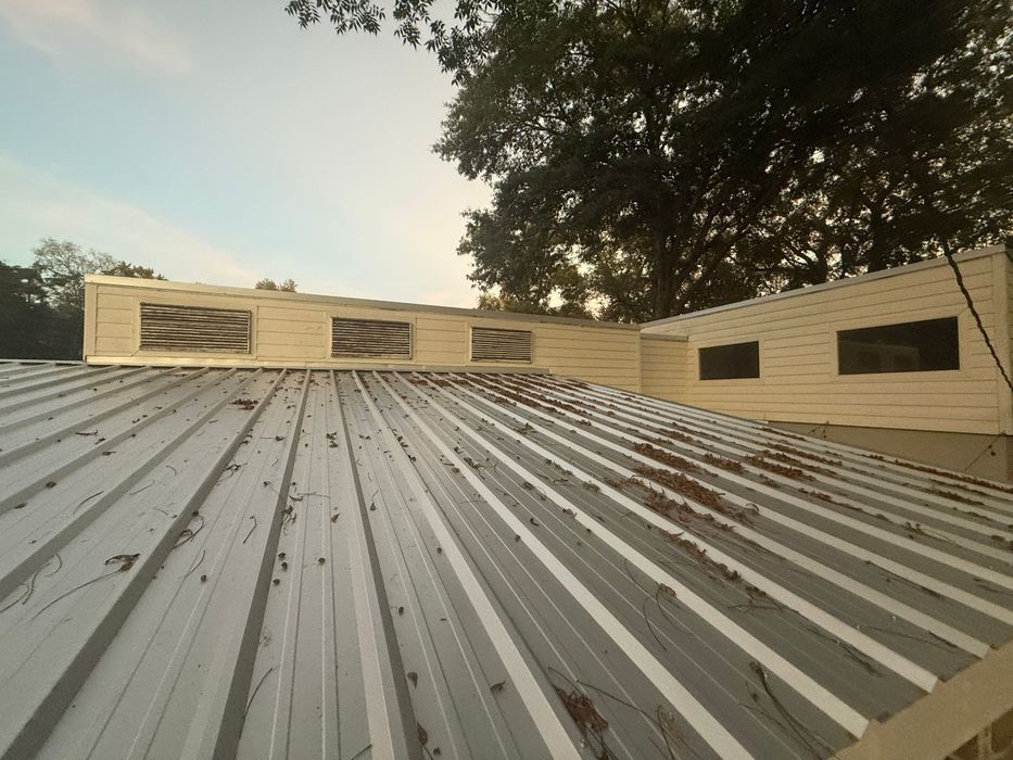 A metal roof of a building with trees in the background.