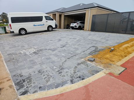 A white van is parked in a driveway in front of a house.