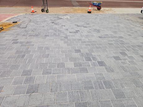 A brick driveway with a wheelbarrow in the background