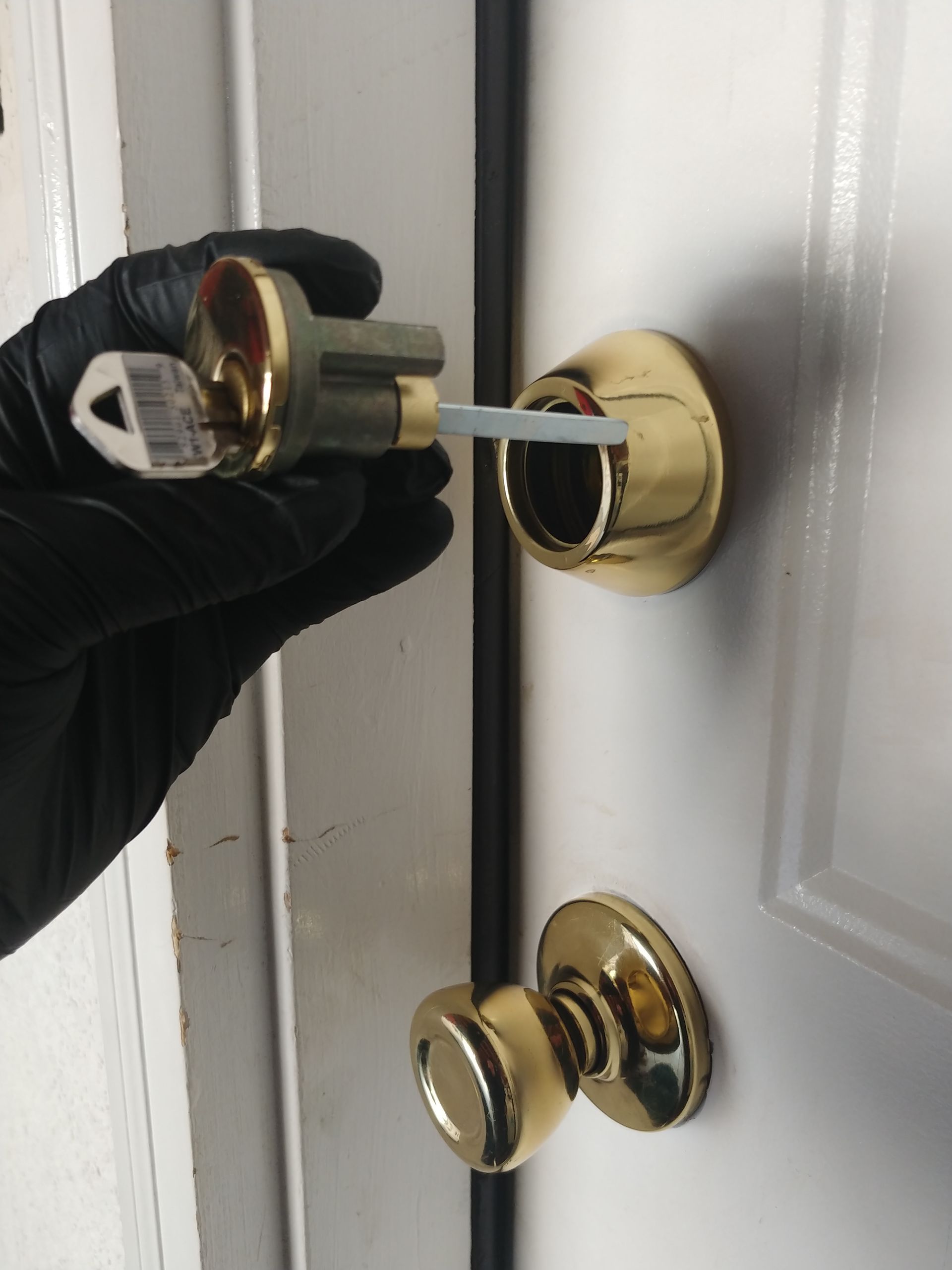 A person in a black glove is holding a key in front of a door