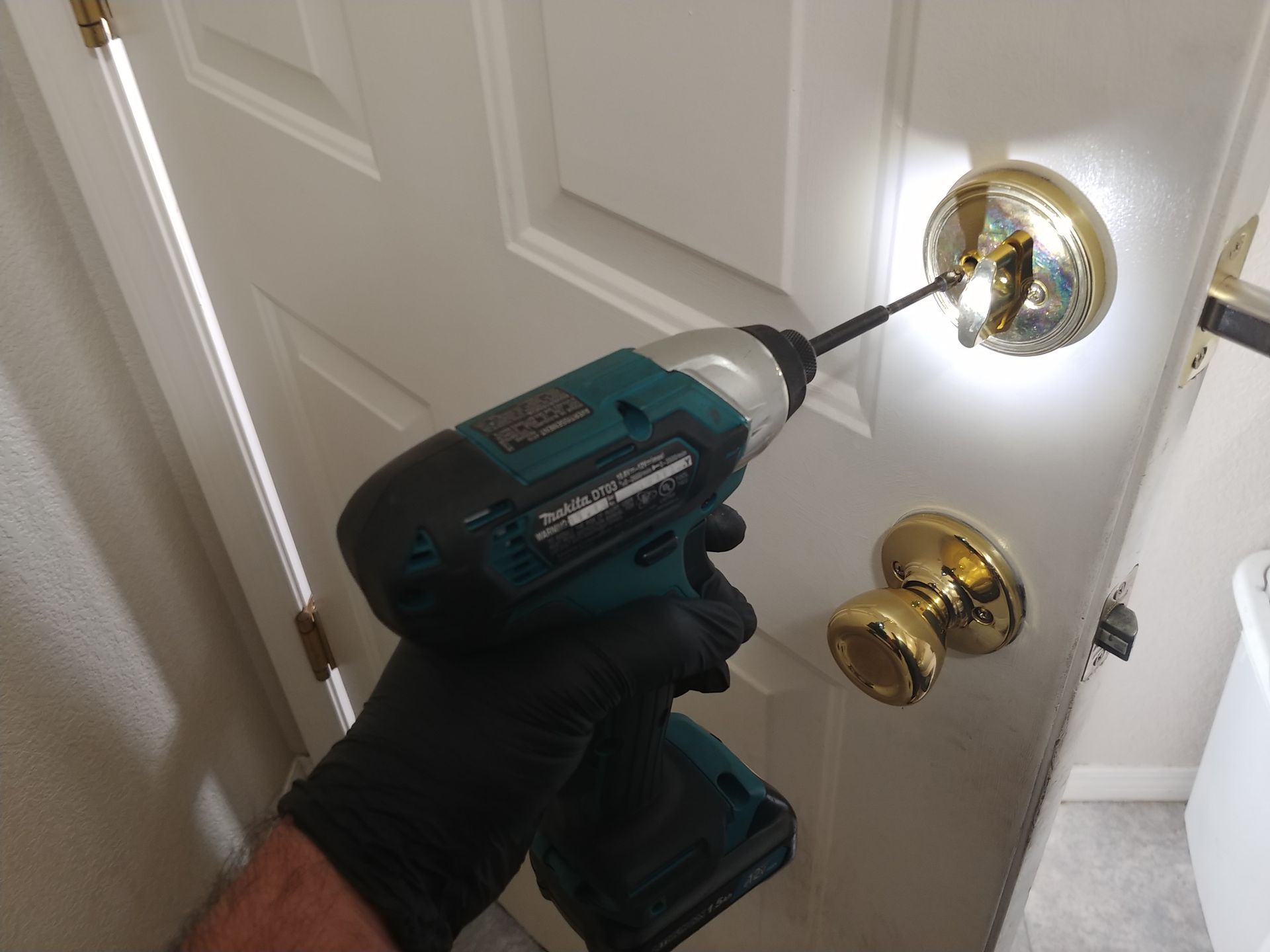 A person is using a makita drill to fix a deadbolt