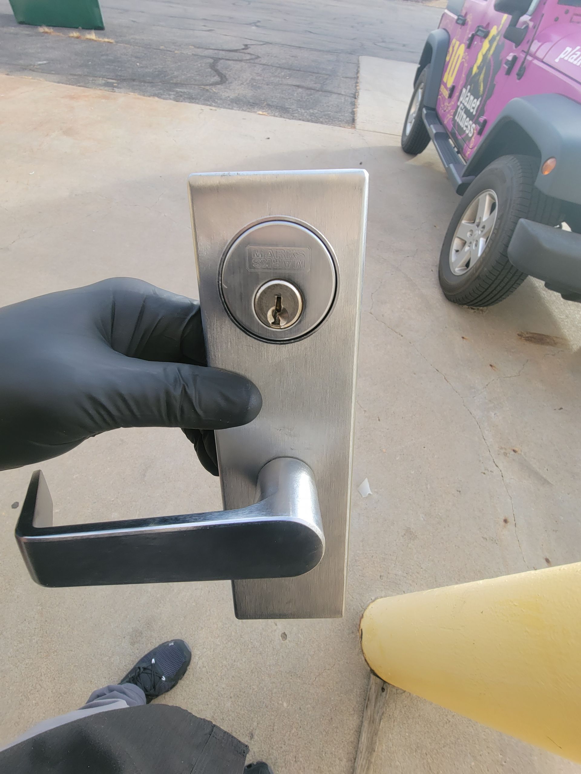 A person wearing black gloves is holding a stainless steel door handle