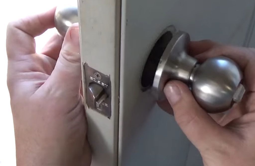A person is holding a door knob in their hand.