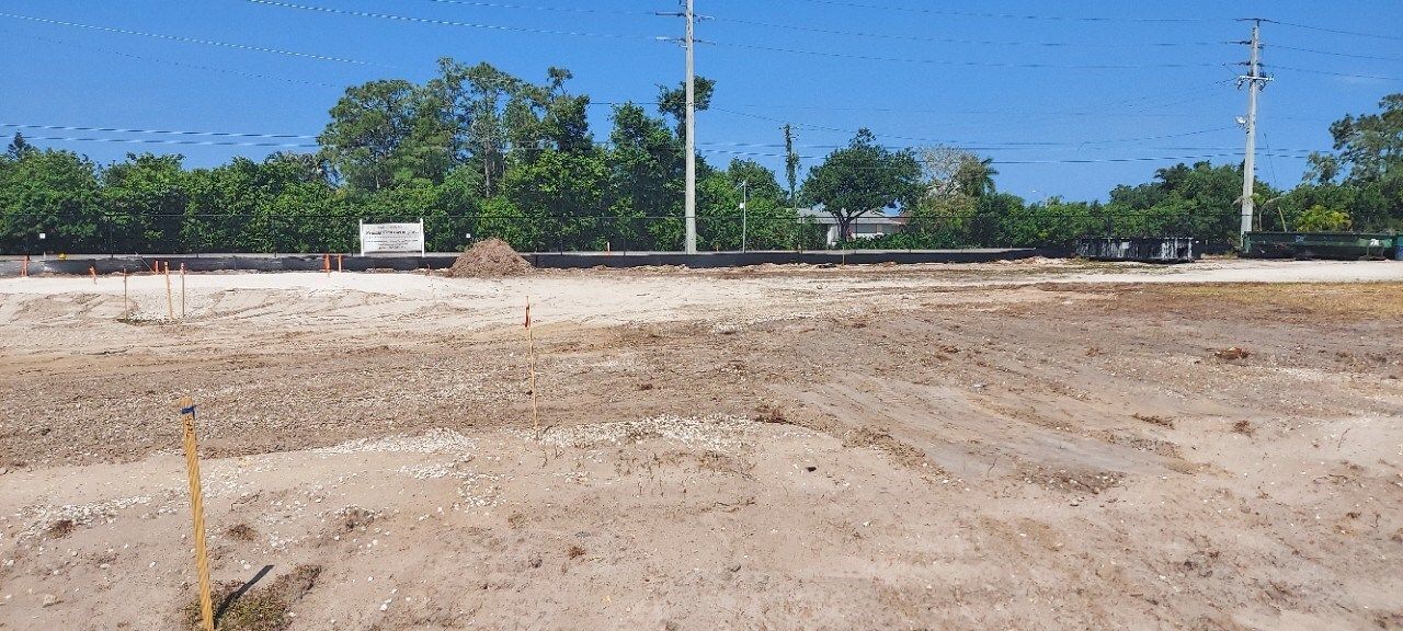 A large dirt field with trees in the background on a sunny day.