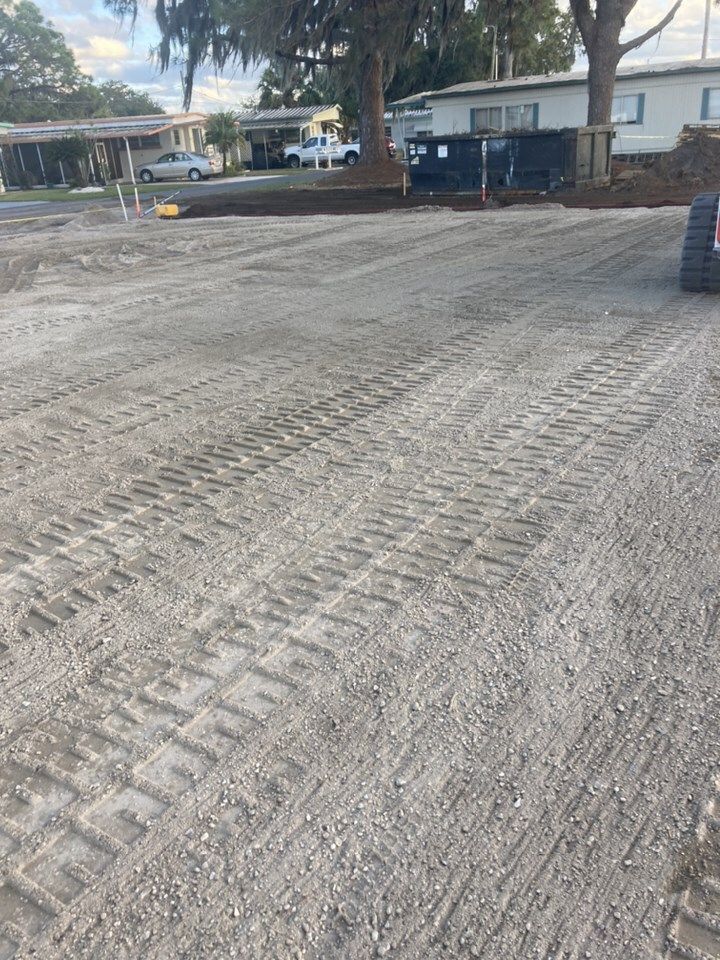 A tractor is driving down a dirt road in a parking lot.