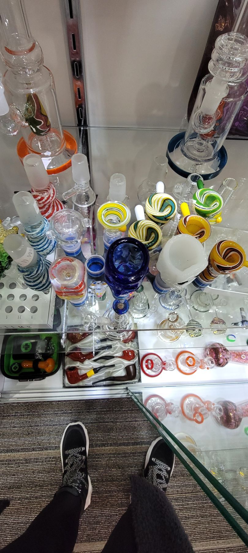Person standing in front of a display of glass smoking pipes and bongs.