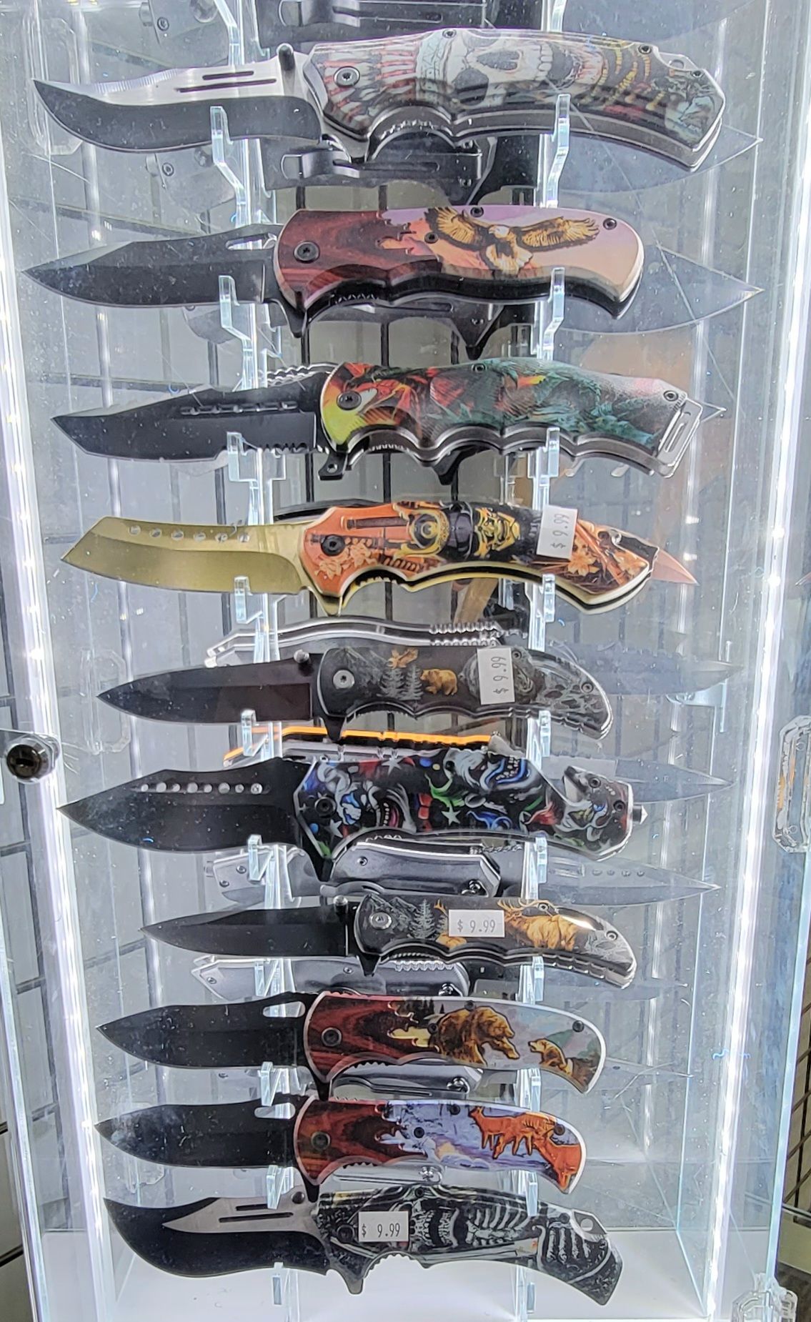 Display case of decorative folding knives with various handle designs.