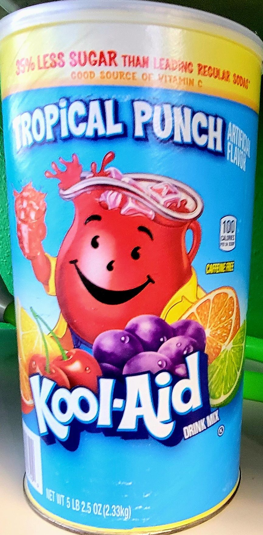 Kool-Aid Tropical Punch container with smiling red pitcher character, fruit illustrations, blue background.
