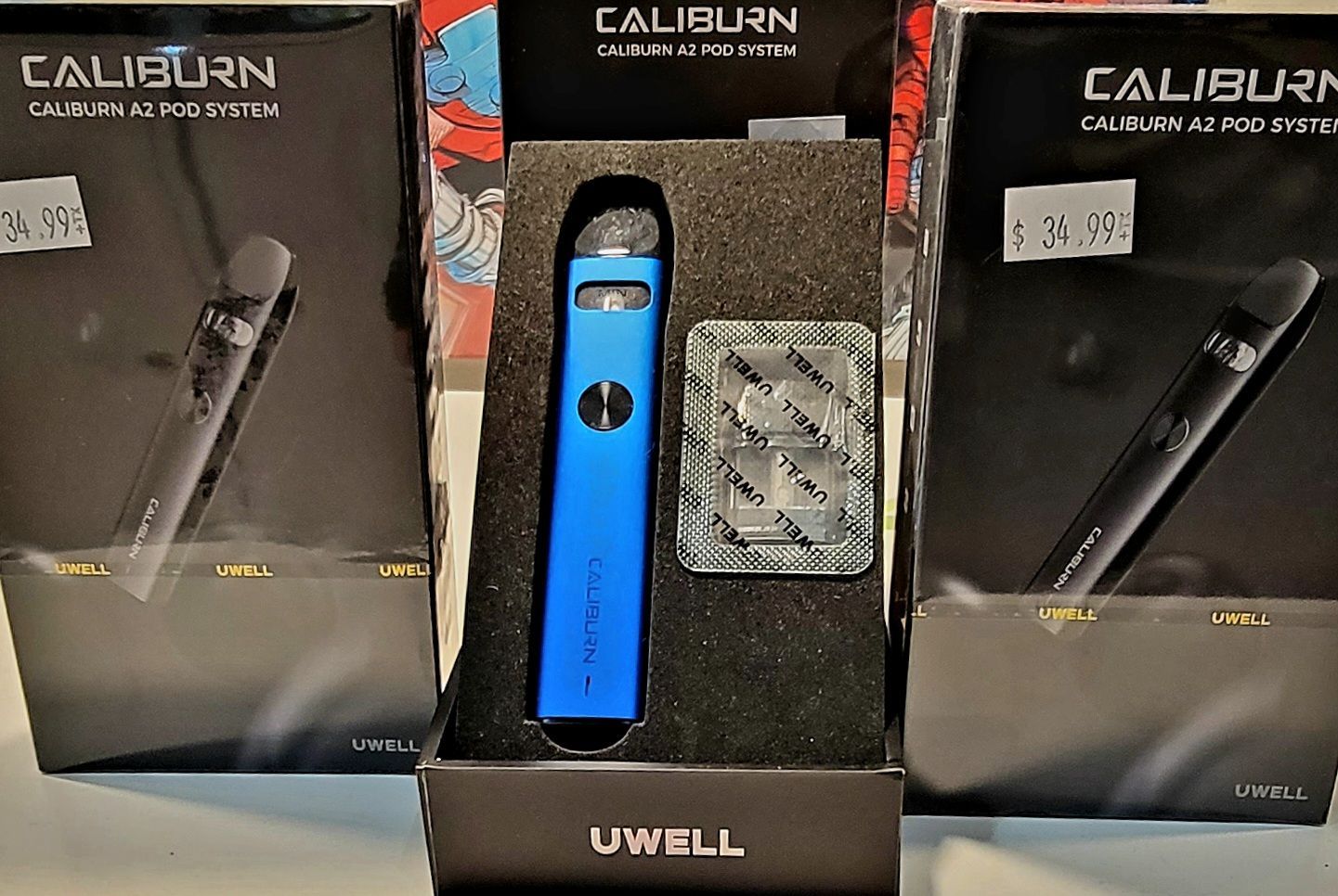 Uwell Caliburn vape kits in boxes, with a blue one open in the center, cartridges included.