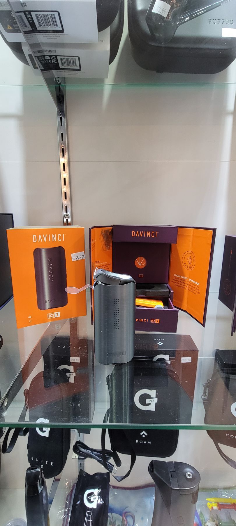 Vape products in a display case. Open boxes with a vape device centered, surrounded by others and accessories.