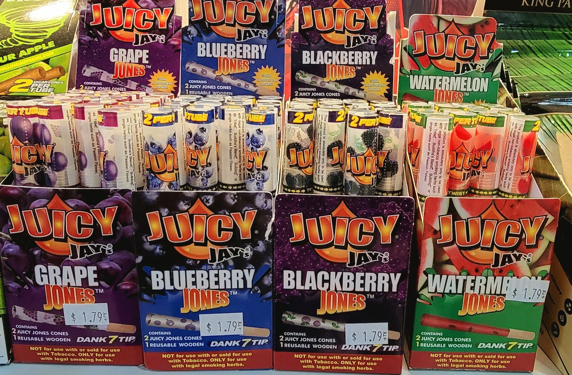 Juicy Jay's flavored rolling papers display: grape, blueberry, blackberry, watermelon. Packages stacked in a store.