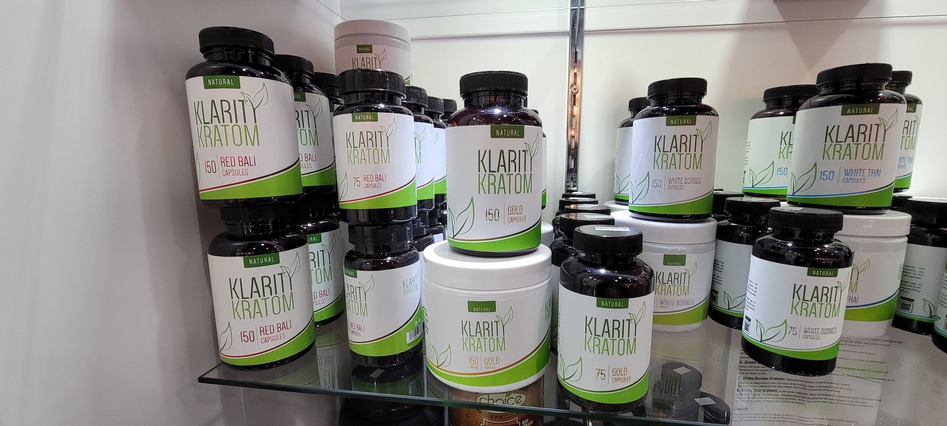 Shelves stocked with multiple bottles and jars of dietary supplements, white labels with green accents.