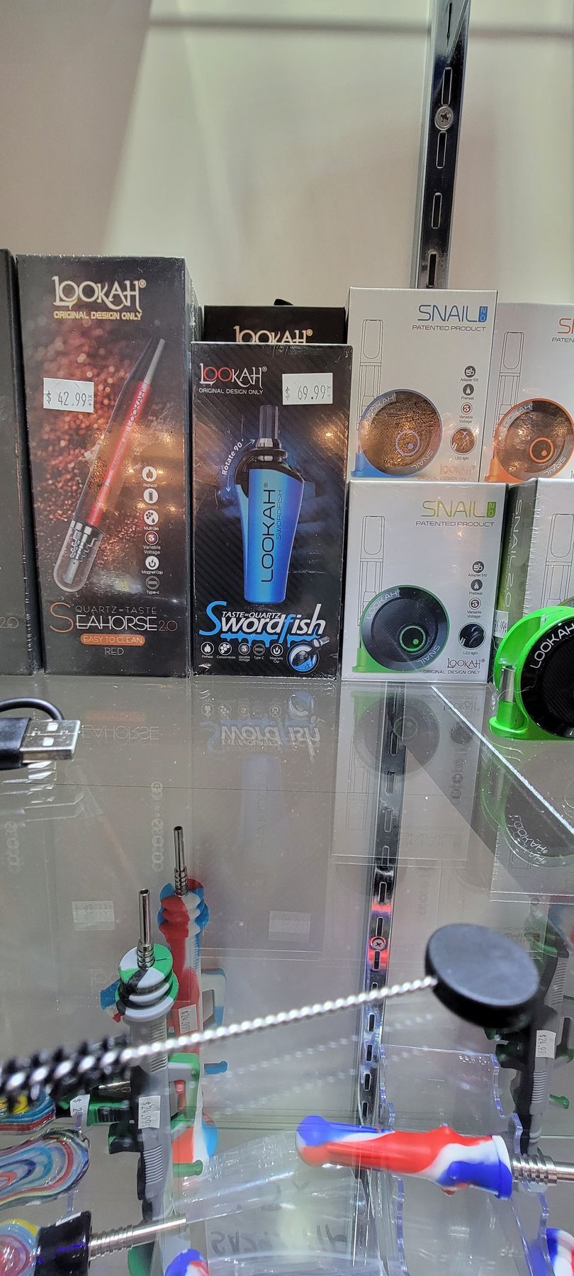 Vape products displayed on a shelf, including boxes with colorful designs and pricing labels.