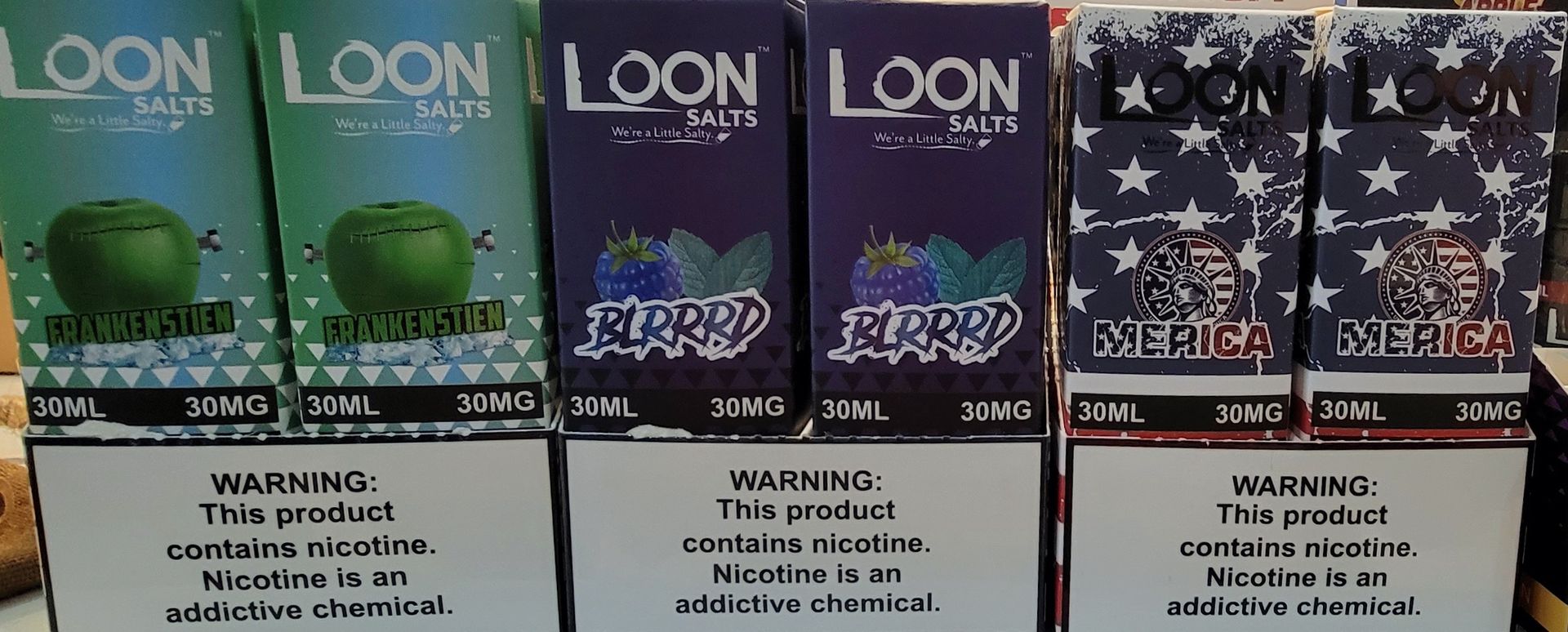 Several Loon Salts vape boxes with different flavors, including apple, blueberry, and America.