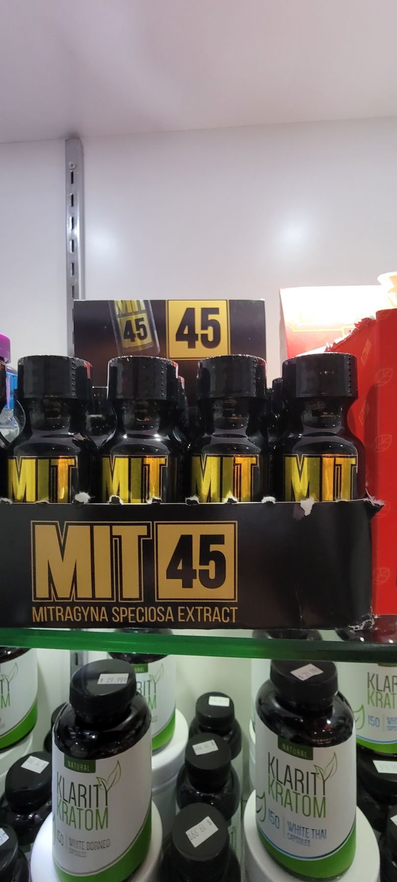 Display of MIT 45 bottles with gold lettering on a store shelf, alongside other supplements in a retail setting.