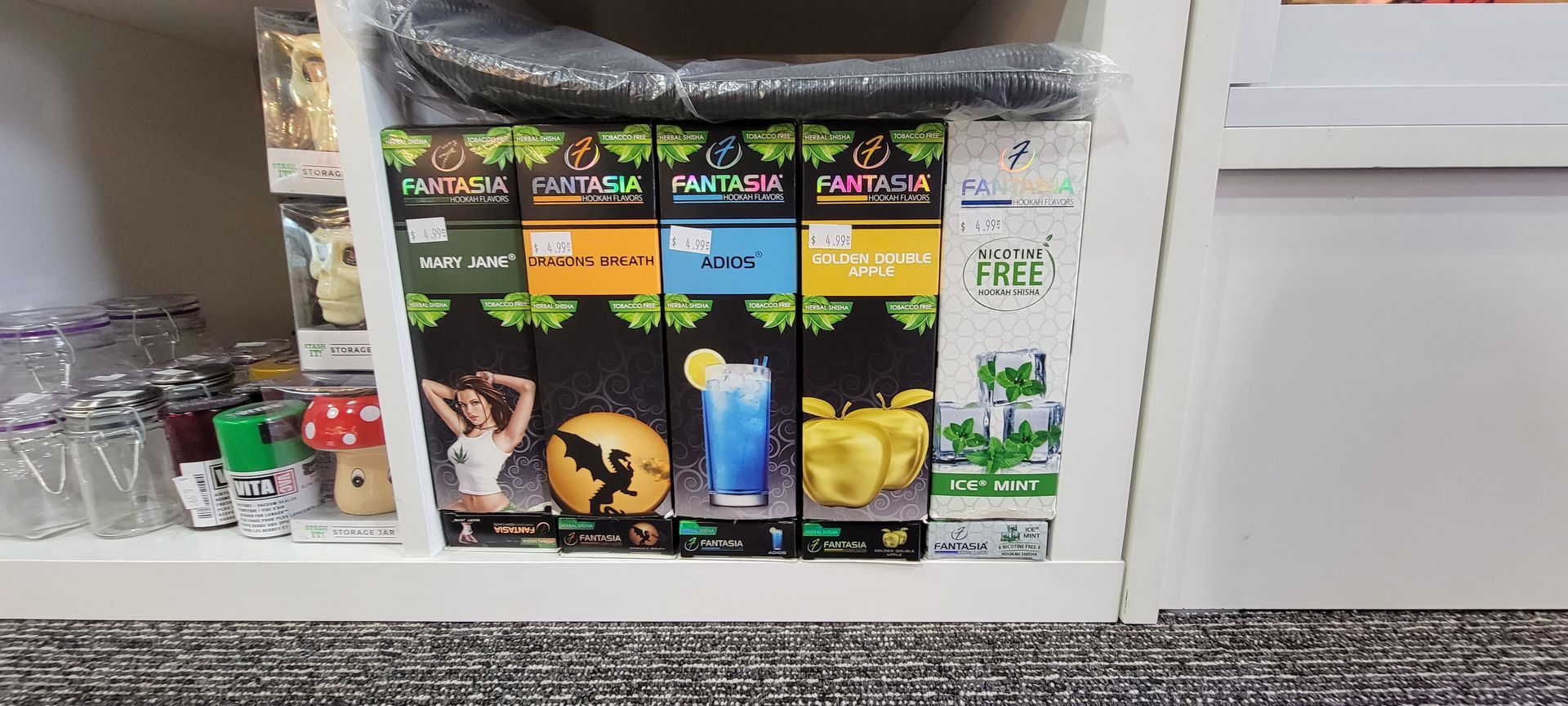 Shelf display of vape products, featuring colorful boxes with illustrations of a woman, a dragon, and fruit.