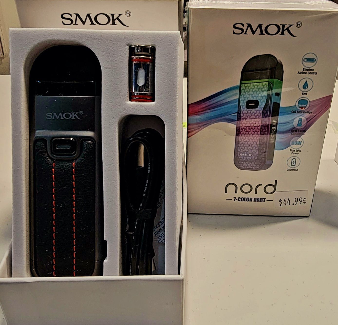 A Smok Nord pod vape kit in its box. The box contains the device, a pod, and a USB cable.