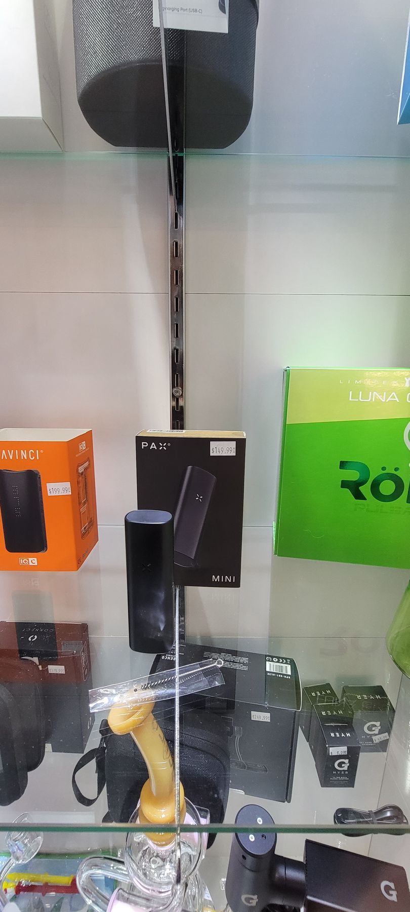 Items displayed in a glass cabinet, including speakers, boxes, and cameras, in a store setting.