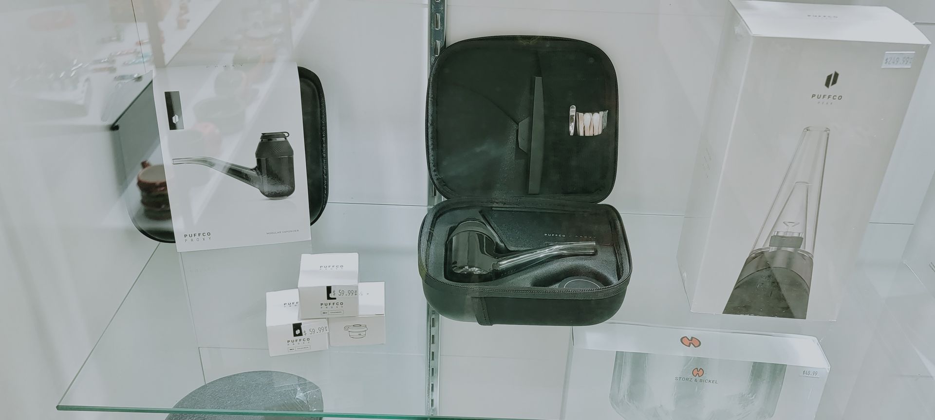 Display case with black vape case, white boxes, and glass smoking devices.