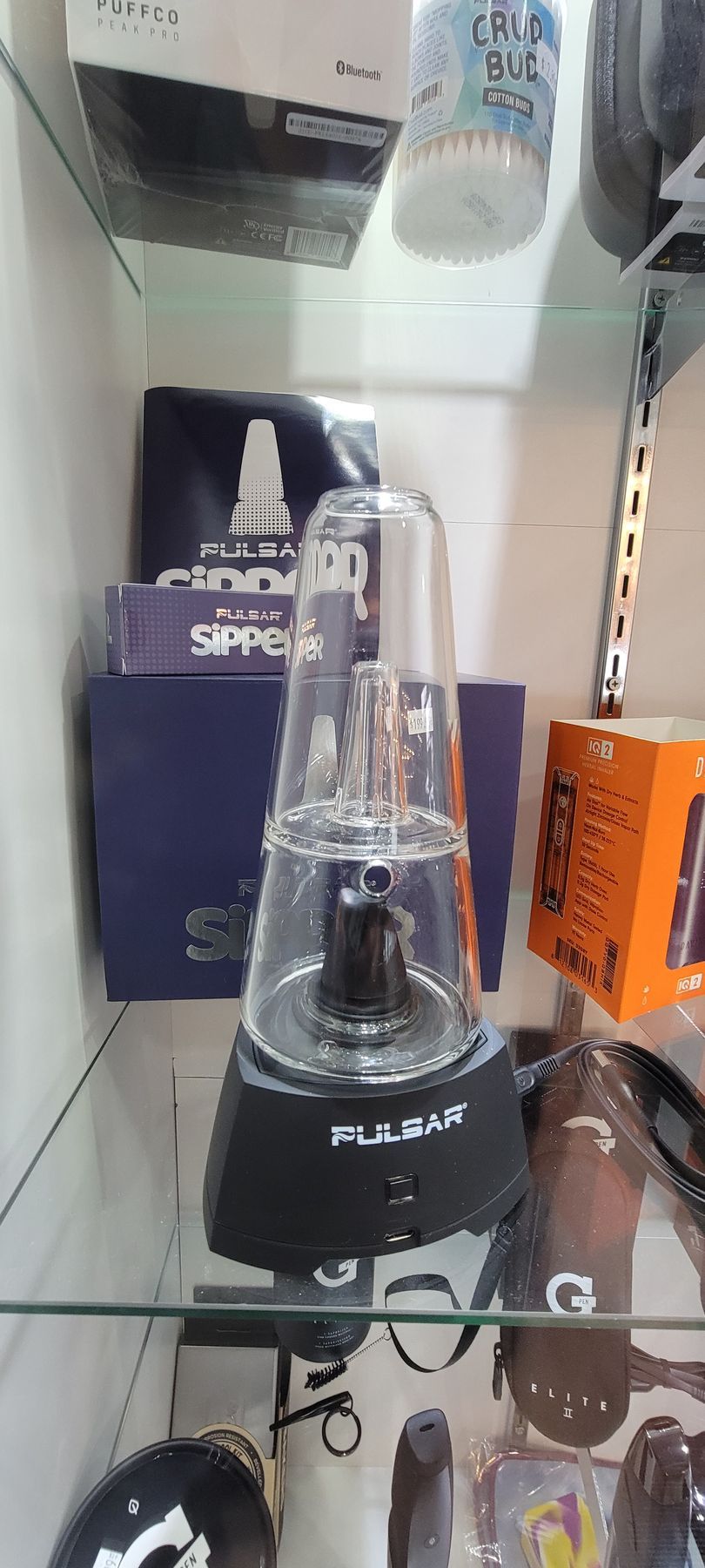 A black and clear Pulsar RIGS vaporizer sits on a shelf in a shop.