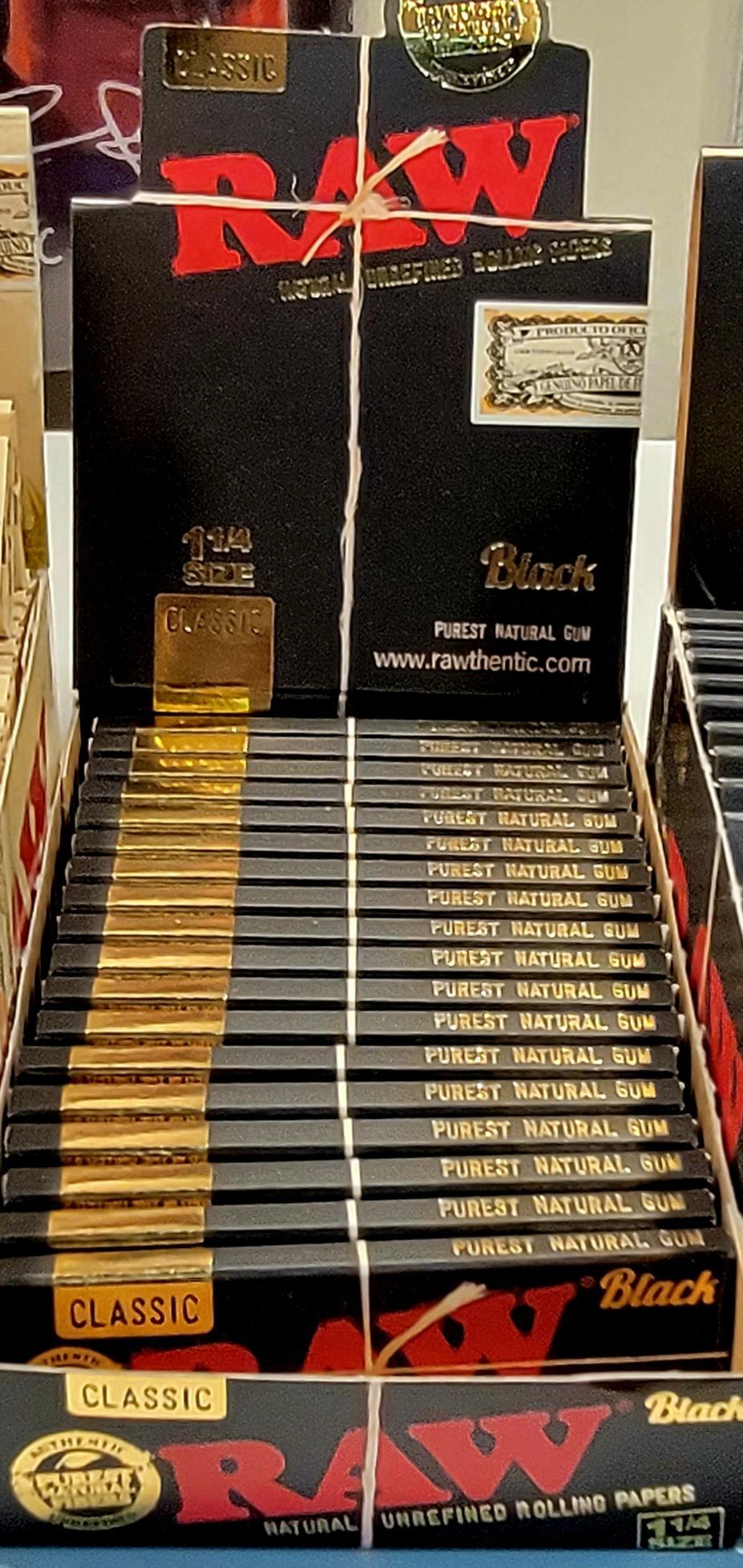 Display of RAW black rolling papers. Black boxes with red logos and gold accents.