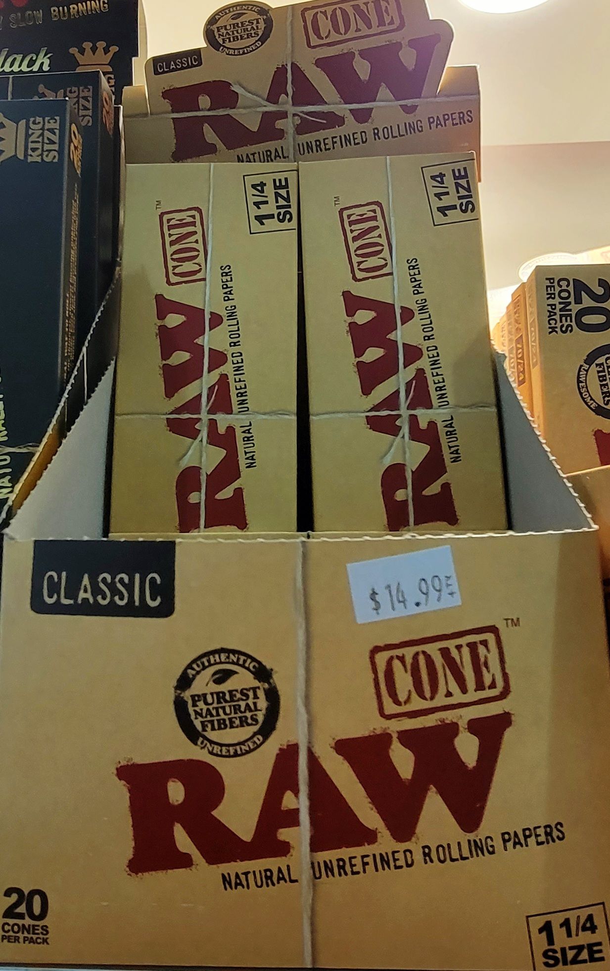 Display of RAW brand cone rolling papers in a store. Brown boxes with red lettering.