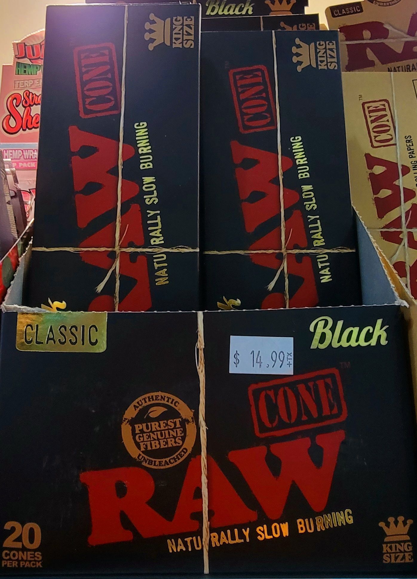 Boxes of RAW Classic and Black cone rolling papers displayed on a shelf in a store.