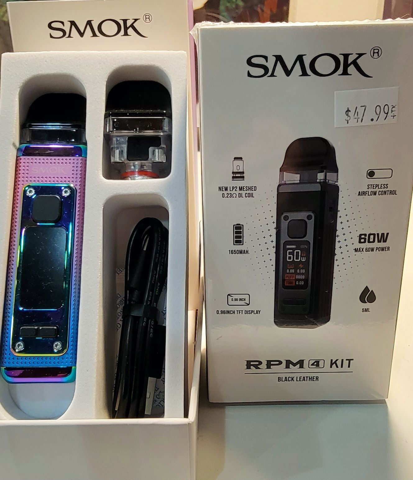 Smok RPM 4 Kit in open box: iridescent vape device, cartridge, cable, and box with display screen.