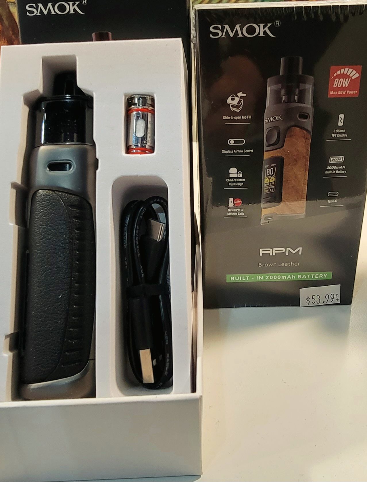 SMOK RPM vape kit in box, featuring a black and silver vape, charger, and coil.