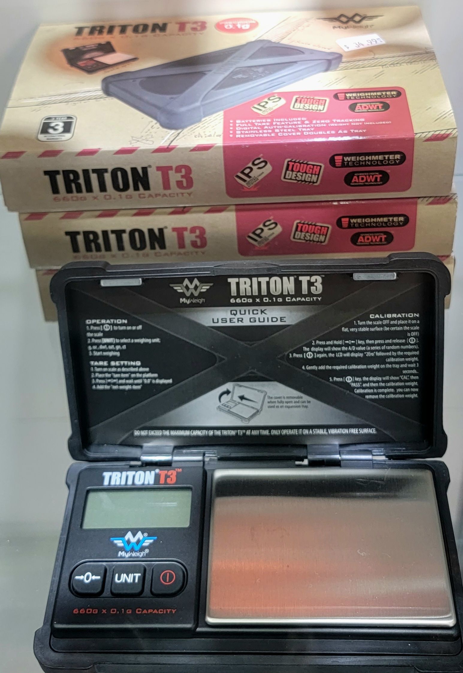 A black digital scale with a silver weighing surface, two boxes labeled 