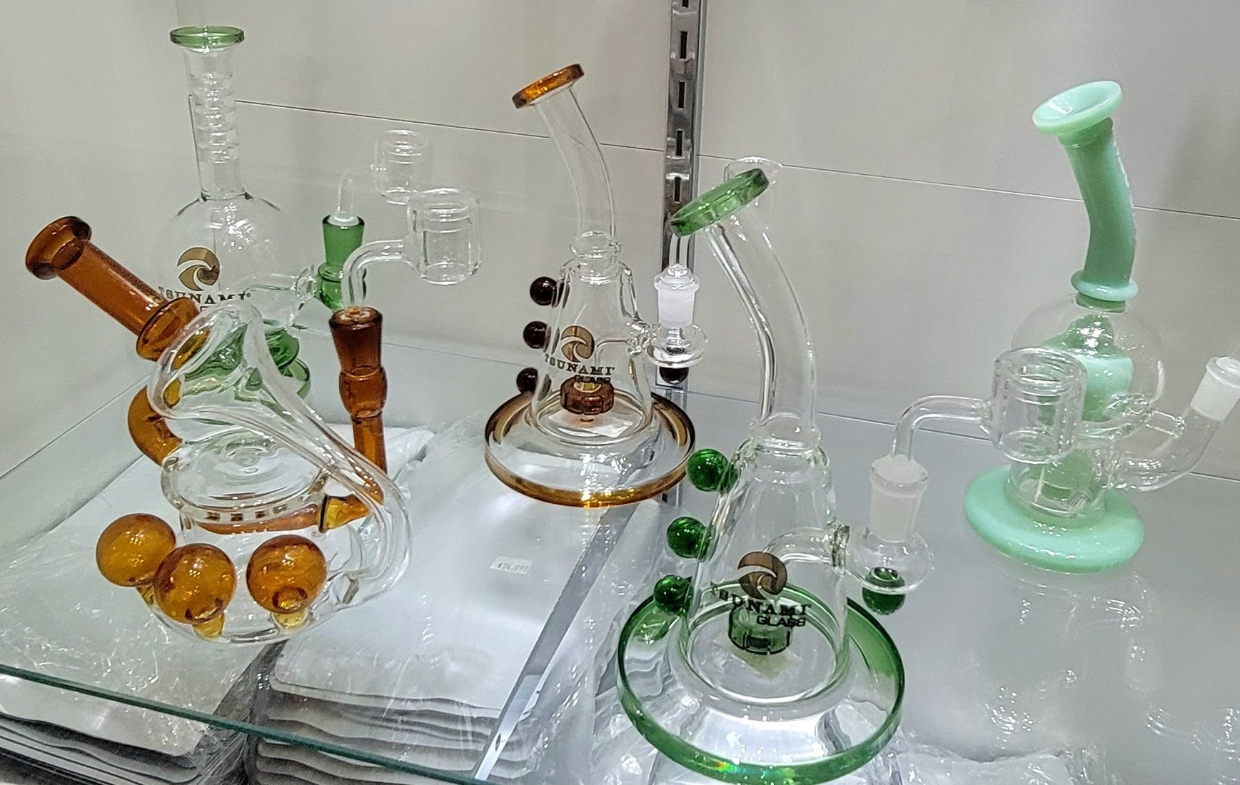 Glass bongs in various styles and colors on a shelf.