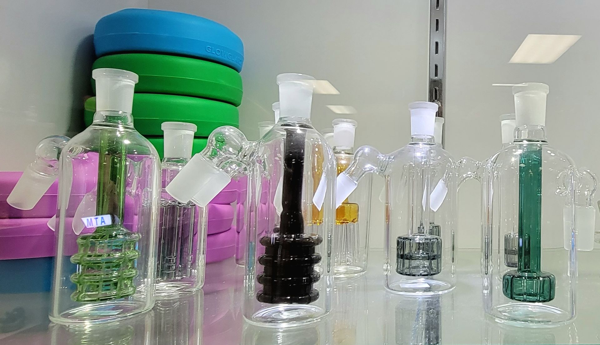 Glass water pipes displayed in a store, various colors, with green, black, and clear components.