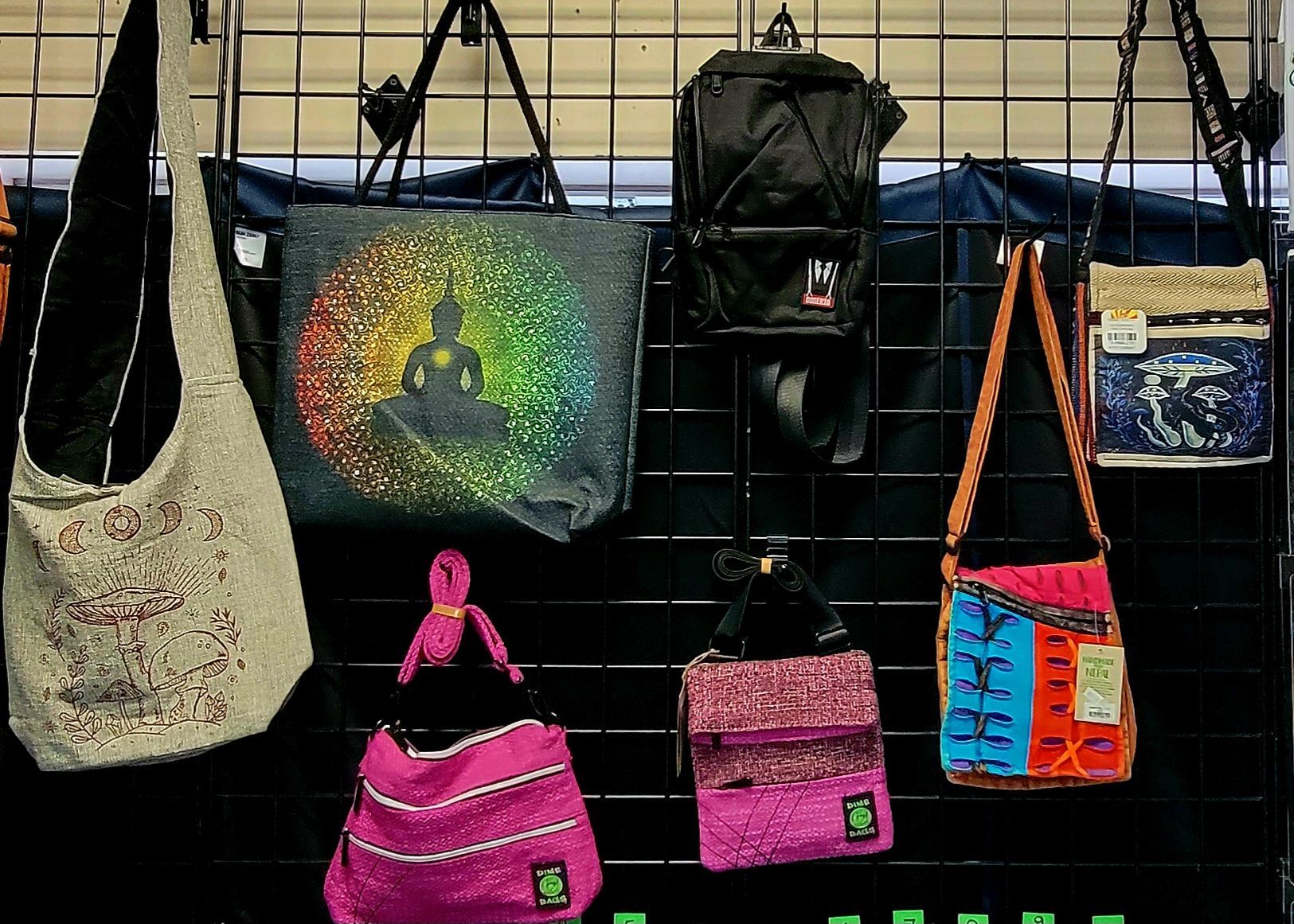 Bags of various styles and colors, some with designs, hanging on a black display grid.