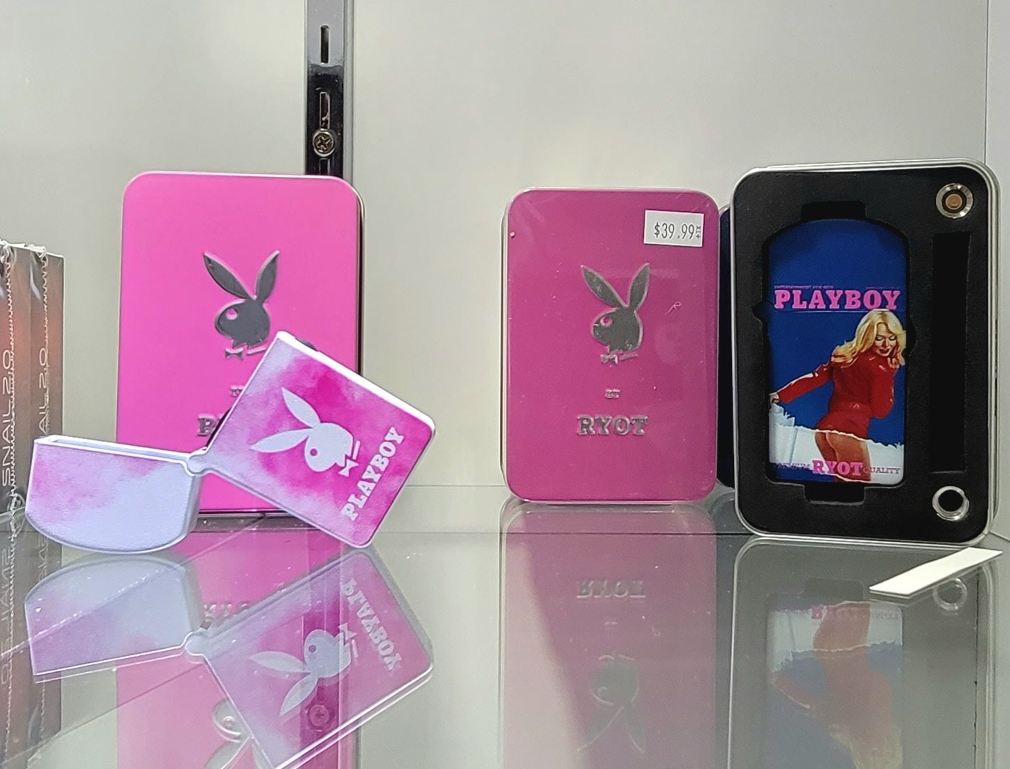 Pink Playboy branded items on a shelf: sunglasses, boxes, and a phone case.