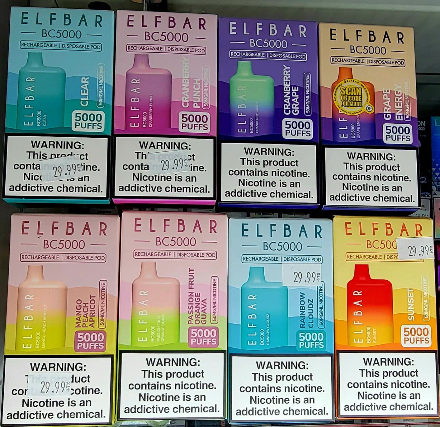 Boxes of Elf Bar BC5000 vape pens with different fruit flavors and nicotine warnings.