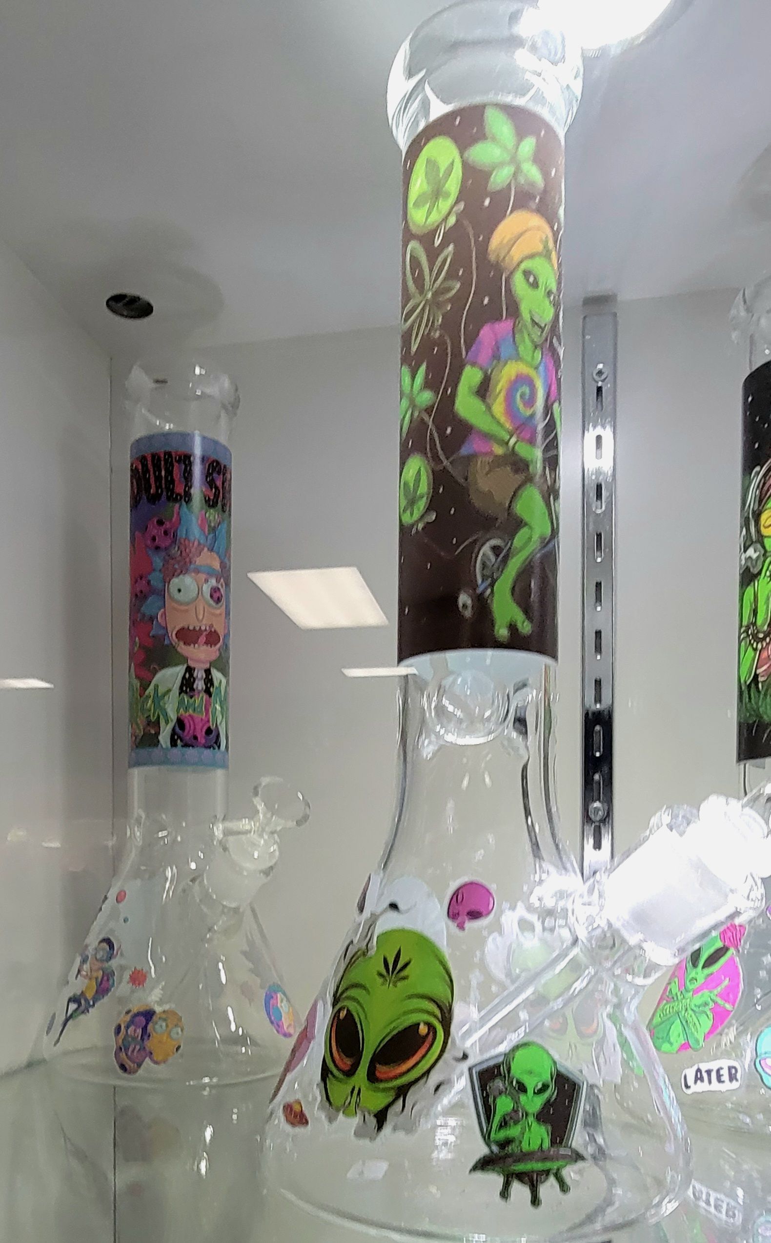 Glass bongs with alien and cartoon designs on display in a store.