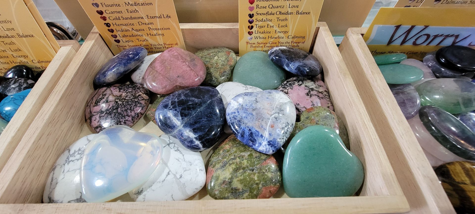 A display of heart-shaped crystals in wooden bins, with small signs listing their properties.