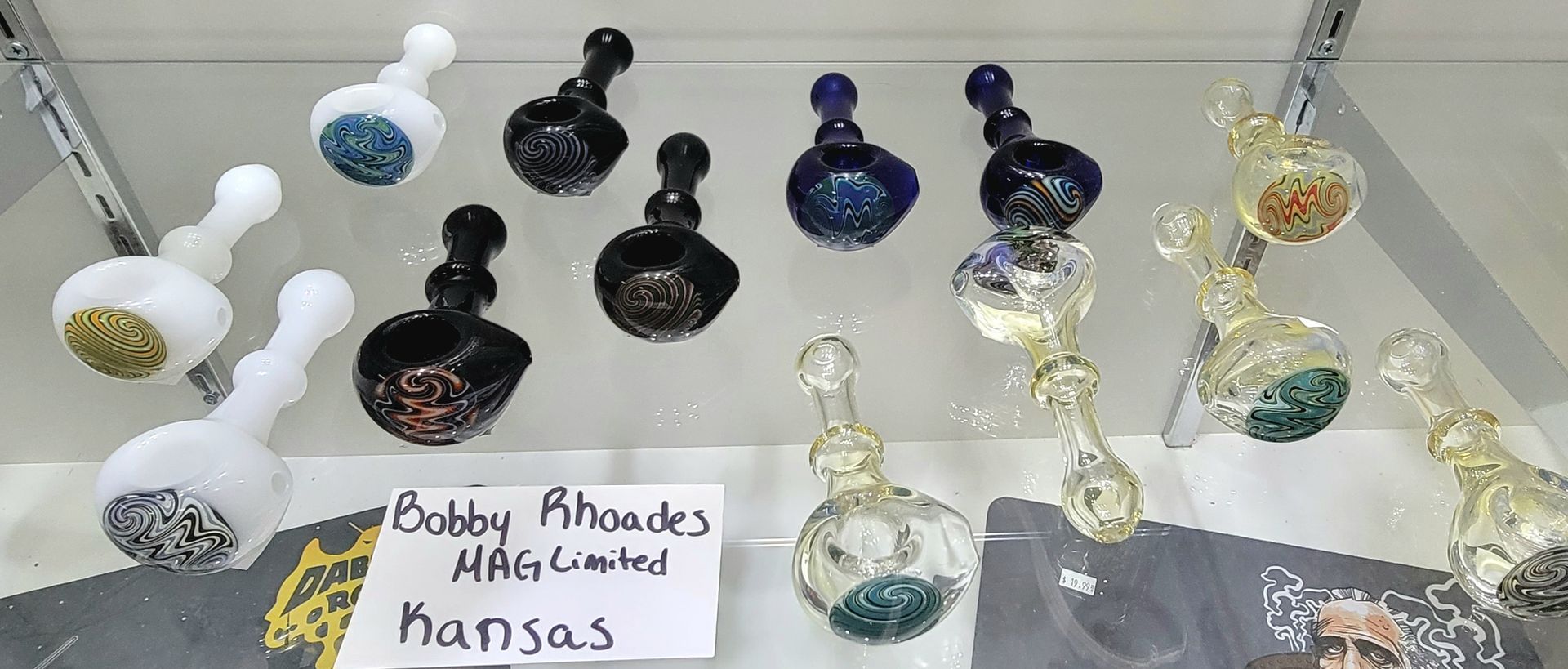 Glass pipes in various colors on display, with a sign reading 