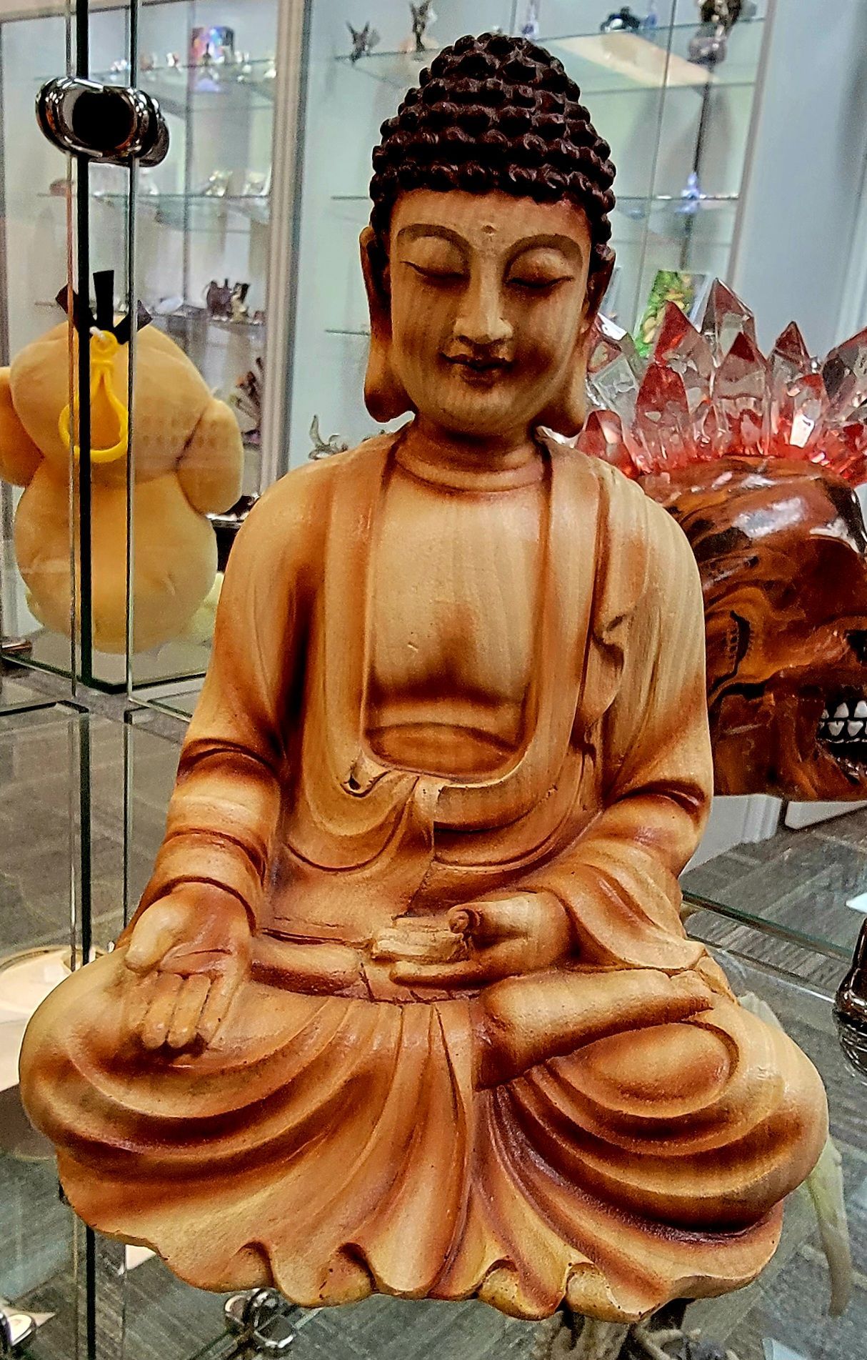 Wooden Buddha statue in seated meditation, hands in lap, eyes closed, light brown wood.