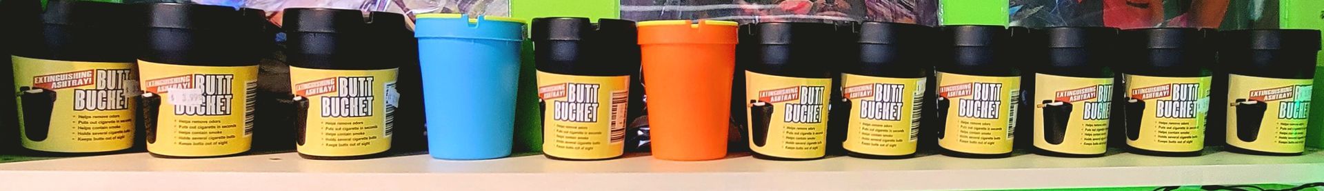 Bottles with black caps, yellow labels, and colored lids (blue, orange) lined up on a shelf.