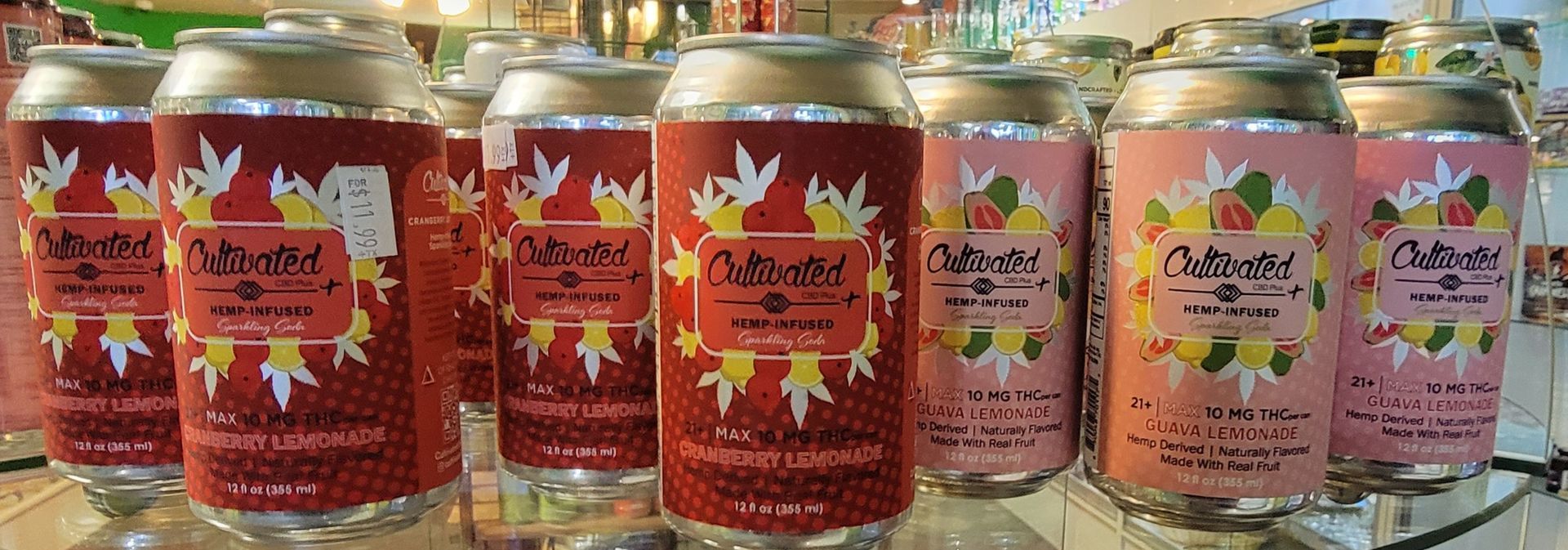 Cans of craft beer with red and pink labels, set in a store.