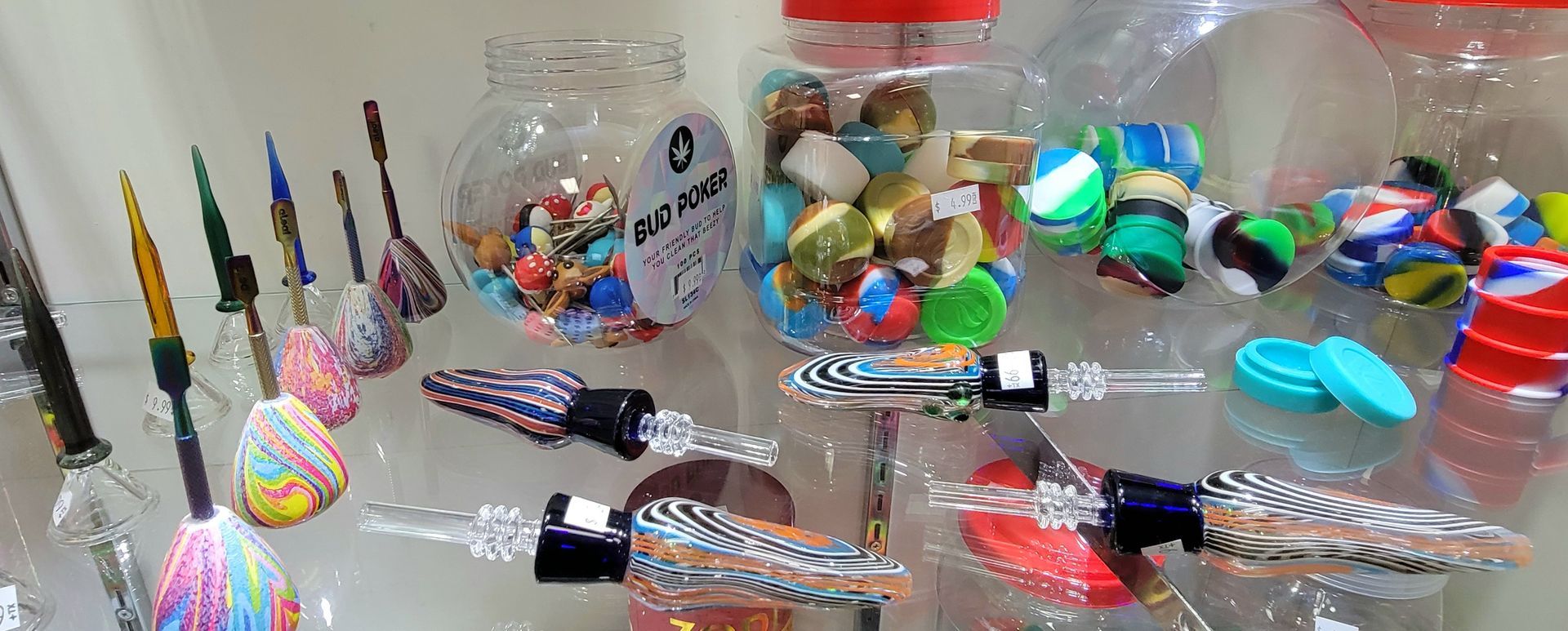 Display of colorful glass art, including decorative stems and containers filled with marbles and trinkets.