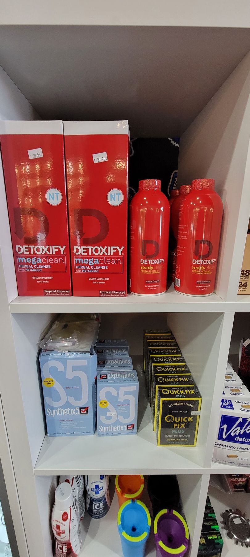 Shelves stocked with health and wellness products in red, blue, black, and gold packaging.