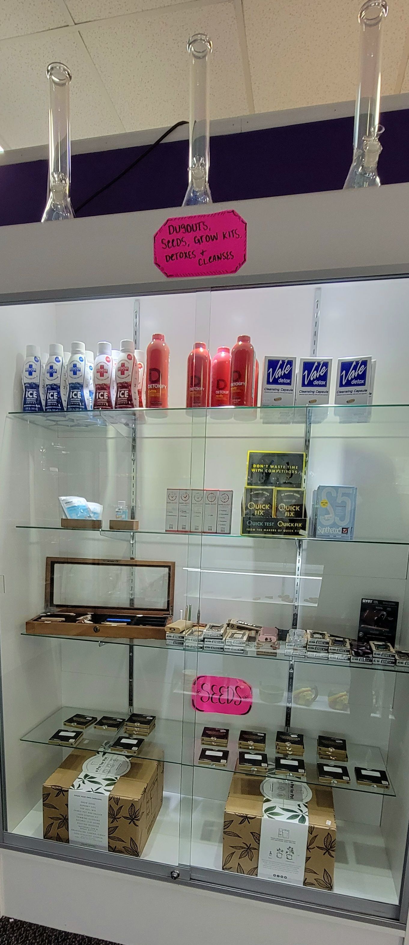 A glass display case in a store, filled with merchandise. Pink signs hang in the case.