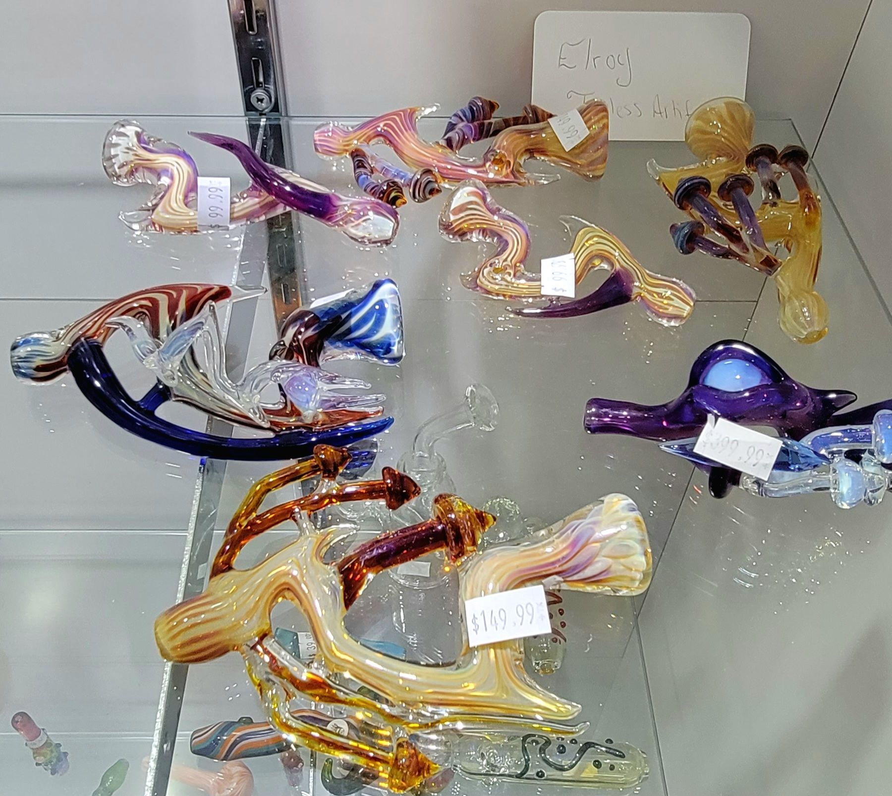 Glass pipes of various colors displayed on a shelf in a shop.