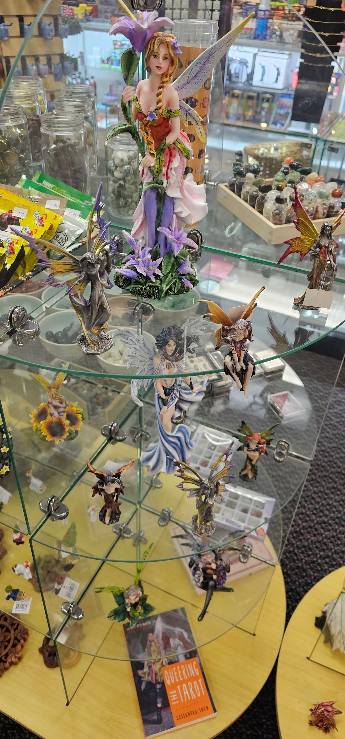 Fairy figurines displayed on a glass shelf inside a shop.